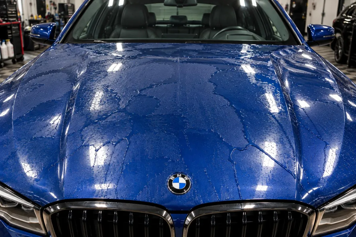 Uncoated blue BMW hood with water sheeting across the paint